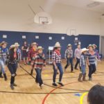 Kids dressed like cowboys performing a dance.