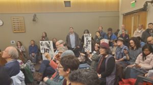 Room full of attendees holding various signs