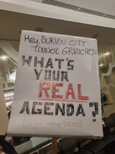 Sign that reads "Hey, Burien City Council Grinches: What's your real agenda? ('Cuz your timing SUCKS!)"